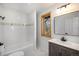 Well lit bathroom with shower-tub, white tile, and a dark wood vanity at 9350 W Florida Ave, Lakewood, CO 80232