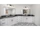 Bathroom featuring double sinks with granite countertops, white cabinets, and mosaic tiled floors at 9350 W Florida Ave, Lakewood, CO 80232