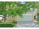 Home exterior featuring a two-car garage, well-kept lawn, and a mature tree at 10231 Spotted Owl Ave, Highlands Ranch, CO 80129