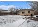 Spacious backyard covered in snow, featuring a brick house, wooden fence, and string lights at 1534 Rosemary St, Denver, CO 80220