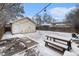 Snowy backyard with a detached garage, a wooden bench, and string lights to create a cozy atmosphere at 1534 Rosemary St, Denver, CO 80220