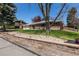 Well-kept brick home featuring a charming front yard and mature trees under a sunny, blue sky at 12375 W 19Th Pl, Lakewood, CO 80215