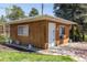 A wood paneled outbuilding with white trim, windows, door, and concrete path sits beside a well manicured lawn at 12375 W 19Th Pl, Lakewood, CO 80215