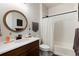 Well-lit bathroom with a dark wooden vanity, round mirror, and shower-tub combination, creating a cozy and functional space at 865 Oleander St, Castle Rock, CO 80109