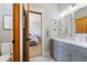 Bright bathroom featuring a double vanity with gray cabinets and a view into the bedroom at 9 Amaranth Dr, Littleton, CO 80127