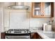 Bright kitchen features stainless steel stove, mosaic tile backsplash and dark wood cabinets under a modern vent hood at 315 S Franklin St, Denver, CO 80209