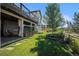 Landscaped backyard with a stone patio, mature trees, and wooden fence at 21064 Woodside Ln, Parker, CO 80138