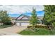 Inviting home with lush green lawn and landscape beds, brick details, and a three-car garage at 21064 Woodside Ln, Parker, CO 80138