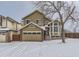 Tan two-story house with a large window and snow covered lawn at 1218 Ascot Ave, Highlands Ranch, CO 80126