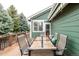 A relaxing outdoor deck is set for dining with seating for six and views of mature trees and the home's green exterior at 13263 Niwot Trl, Broomfield, CO 80020