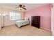 Bedroom featuring plush carpet, pink accent wall, a ceiling fan, and white trim at 22962 Briar Leaf Ave, Parker, CO 80138