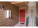 Exterior view of front entrance with a red front door and a light fixture on a wood paneled wall at 4899 S Dudley St # 15B, Littleton, CO 80123