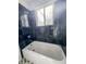 A bathroom features black marbleized tiling around a bright white tub with shower head and fixtures at 4777 S Olathe St, Aurora, CO 80015
