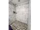 Close up of the bathroom shower with grey and white marble tiles and unique patterned shower floor at 4777 S Olathe St, Aurora, CO 80015