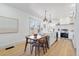 Bright kitchen with white cabinets, an island with pendant lights, and a wooden dining table near a large window at 5612 Ammons St, Arvada, CO 80002