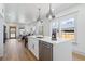 Modern kitchen with white cabinets and island, stainless steel appliances, seamlessly connecting to the living area at 5612 Ammons St, Arvada, CO 80002