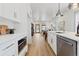 Open kitchen with white cabinets, stainless steel appliances, and an island, seamlessly connecting to the living area at 5612 Ammons St, Arvada, CO 80002