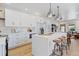 Modern white kitchen featuring a large island with bar seating, stainless steel appliances, and light wood flooring at 5612 Ammons St, Arvada, CO 80002