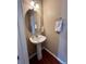 Small bathroom with a round mirror, pedestal sink, and red floor at 19246 E Idaho Pl # 102, Aurora, CO 80017