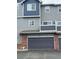 Gray townhouse, with a gray two car garage, brick accents, and blue accents at 19246 E Idaho Pl # 102, Aurora, CO 80017