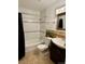 Bathroom showcasing tiled shower-tub, decorative mirror, sink with dark wood cabinetry at 9019 E Oxford Dr, Denver, CO 80237