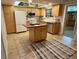 Bright kitchen with light wood cabinets, tile floor, island, white appliances, and unique ceiling detail at 9019 E Oxford Dr, Denver, CO 80237