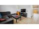 Living room featuring tile floors, a dark sofa, and a TV; a bright and open space at 9019 E Oxford Dr, Denver, CO 80237