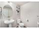 Simple powder room with a pedestal sink, round mirror, modern wall art, and a white toilet and towel at 4755 Memphis St # 2, Denver, CO 80239