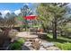 Landscaped backyard features pond, dining table, and a red umbrella at 5055 Mcclure Ln, Castle Rock, CO 80108