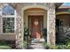Inviting front entrance with a wood door, stone columns, decorative plants, and elegant details at 5055 Mcclure Ln, Castle Rock, CO 80108