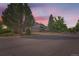 Charming two-story home featuring a well-manicured lawn and mature trees against a vibrant evening sky at 3777 S Walden St, Aurora, CO 80013