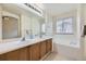 Bathroom with dual sink vanity, large mirror, soaking tub and large window with blinds at 6079 W Prentice Ave, Littleton, CO 80123