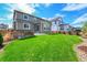 Spacious backyard featuring green grass, a stone-accented wall, and a glimpse of surrounding homes at 821 Boulder Peak Ave, Erie, CO 80516