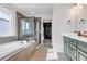 Luxurious bathroom with soaking tub, glass shower, and stylish green cabinetry with patterned tile floor at 821 Boulder Peak Ave, Erie, CO 80516