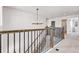 Hallway featuring neutral walls, dark metal railing, carpeted floor, and a decorative light fixture at 821 Boulder Peak Ave, Erie, CO 80516