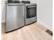 Laundry area with stainless steel front load washer and dryer set on light wood-look flooring at 821 Boulder Peak Ave, Erie, CO 80516