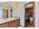 Bathroom featuring a double sink vanity, large mirror, and separate room with toilet and tub with wood paneled wall at 916 W Alder St, Louisville, CO 80027