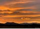 Striking sunset with orange hues over distant mountains, showcasing the natural beauty of the property at 2030 Gyros Cir # 155, Lafayette, CO 80026