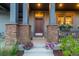 Inviting entrance features a wood door, stone pillar accents, and flower pots flanking the steps at 5735 Boston St, Denver, CO 80238