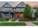 Charming gray home boasts a meticulously landscaped front yard with colorful flowers and a welcoming covered porch at 5735 Boston St, Denver, CO 80238