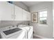 Efficient laundry room with front-load machines and overhead cabinets at 5735 Boston St, Denver, CO 80238