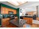 Modern kitchen with granite countertops, wooden cabinets, and black appliances and a view to living room at 1387 Mcintosh Ave, Broomfield, CO 80020