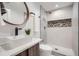 Modern bathroom with sleek fixtures, round mirror, and elegant white marble shower with a stylish accent at 2599 S Cherokee St, Denver, CO 80223
