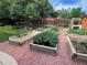 Spacious backyard garden with raised garden beds, brick pathways, and mature trees at 4907 Fenwood Dr, Highlands Ranch, CO 80130