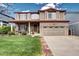 Charming two-story home features a brick facade, covered porch, manicured lawn, and attached two-car garage at 4907 Fenwood Dr, Highlands Ranch, CO 80130