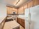 Efficient kitchen with wood cabinets, tile countertops, and white appliances at 16366 E Fremont Ave # 11, Aurora, CO 80016