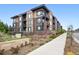 Elegant exterior of a modern apartment building with green grass and walking path in the foreground at 6619 E Lowry Blvd # 101, Denver, CO 80230