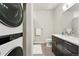 Modern bathroom featuring a sleek vanity with dark wood cabinets and a stackable washer and dryer at 6619 E Lowry Blvd # 101, Denver, CO 80230