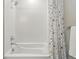 Clean white tub and shower combo with modern fixtures, a tiled wall, and a patterned shower curtain at 6619 E Lowry Blvd # 101, Denver, CO 80230