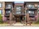 Inviting three-story condo building featuring brick facade, black accents, street-level landscaping and covered entry at 6619 E Lowry Blvd # 101, Denver, CO 80230